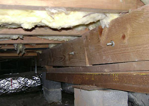 A sagging crawl space with concrete supports and wooden shimming a Westbrook crawl space