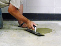 Repairing the cored holes in the concrete slab floor with fresh concrete and cleaning up the Auburn home.