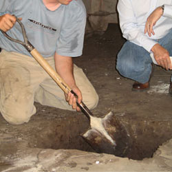 Digging a hole for the engineered fill used in a crawl space support system installation in Waterville