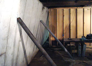 A severely tilting foundation wall propped up by steel beams in Exeter.