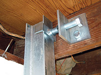 Securing the i-beam system to the top of the floor joist in a foundation wall repair in Auburn.