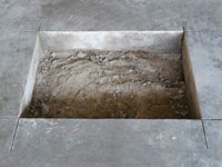 Creating the hole in the garage slab floor during the wall anchor installation in Gardiner.