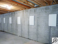 Wall anchor covers installed along a foundation wall that has been straightened in Exeter.