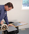 installing a waterproof vapor barrier on a basement floor to prepare for basement carpeting in a Lewiston home